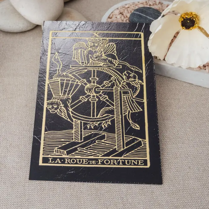 Carte du tarot La Roue de Fortune – illustration du parfum du Tarot TSAEY, photographiée en mise en scène naturelle.